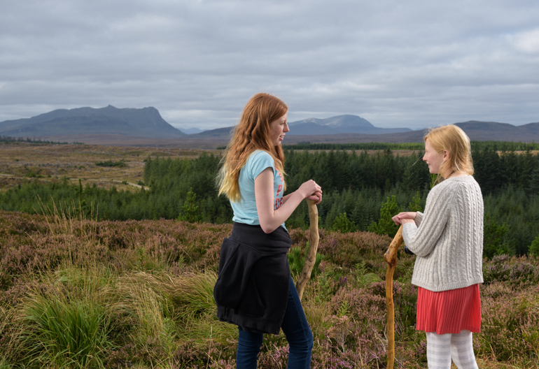 Two young girls stand together with Ben Loyal in background, Borgie Glen, Sutherland