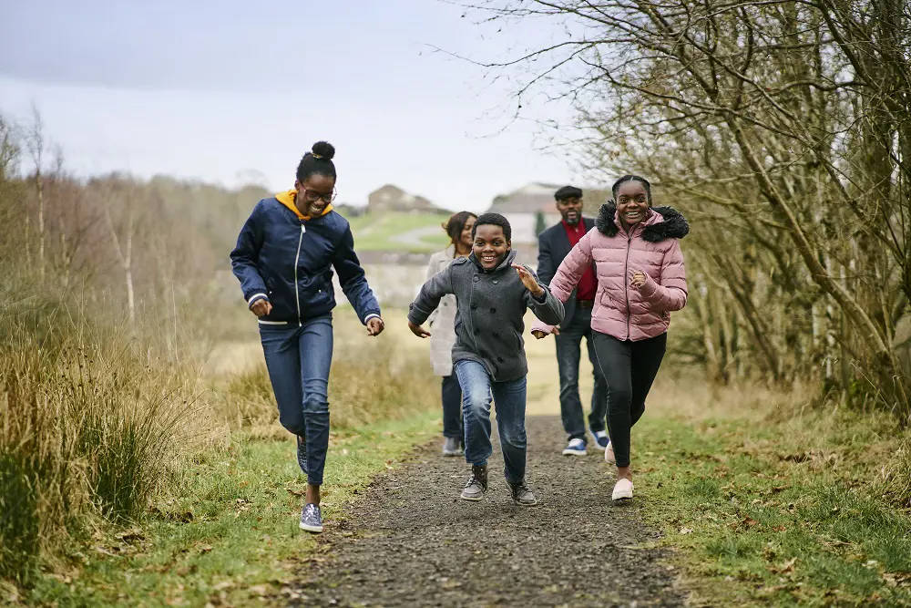 Famliy of five with the three children running towards camera