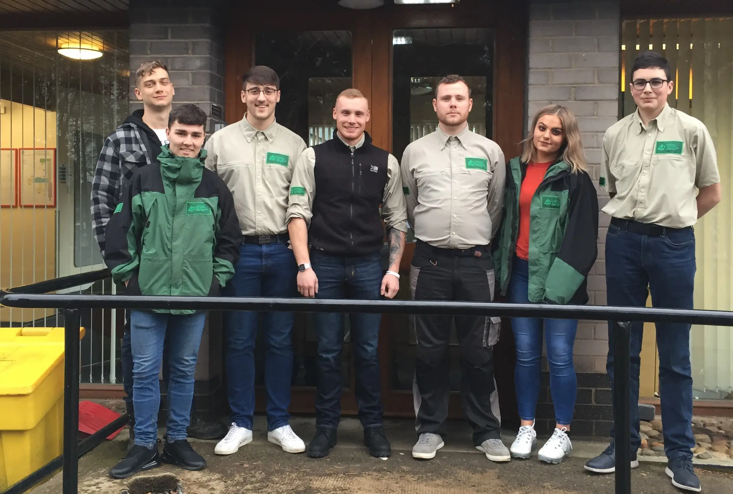 Group of adults standing outside in jackets smiling for the camera