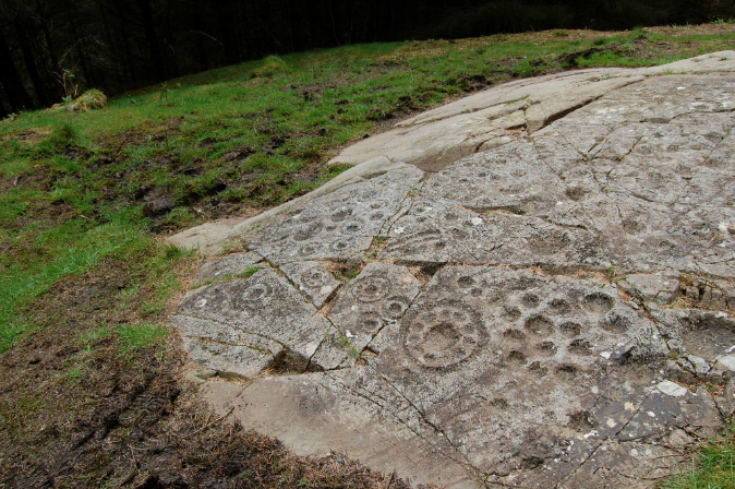 Primitive craving in grey rock embedded in grassy ground