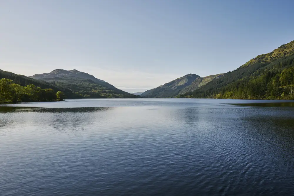 Landscape view of calm open water surrounded by green hillsides