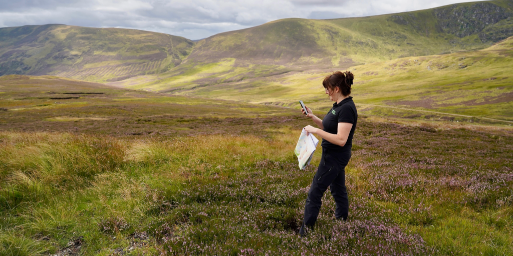Person standing in the glen with a map and GPS device.