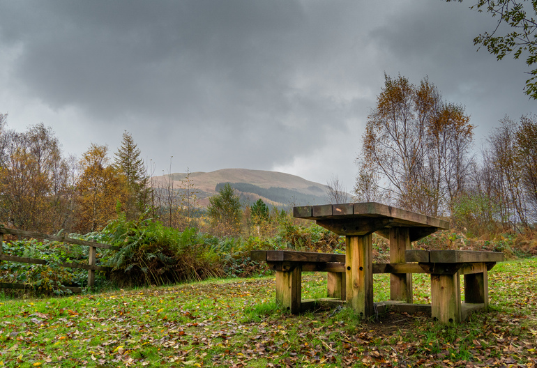 A picnic table with mountains and autumn trees behind it