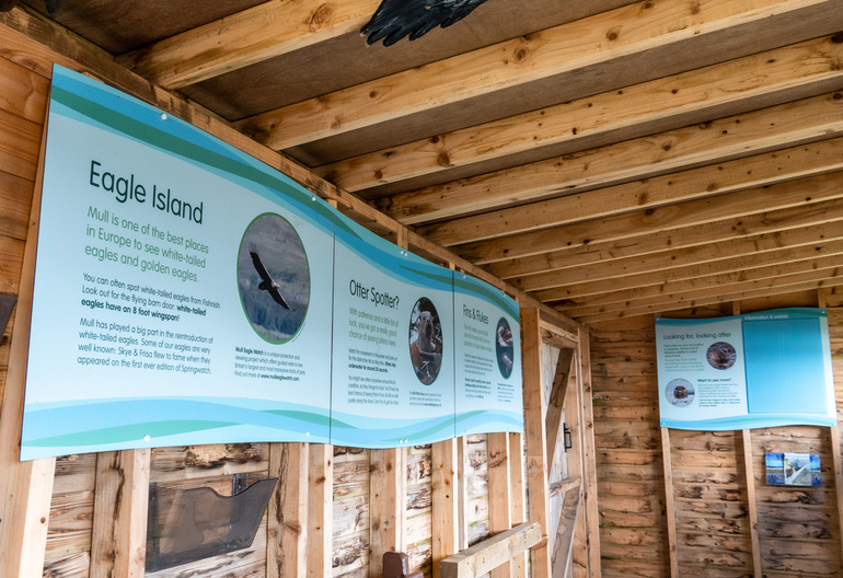  Inside the a wooden wildlife hide with blue signs and pictures of birds