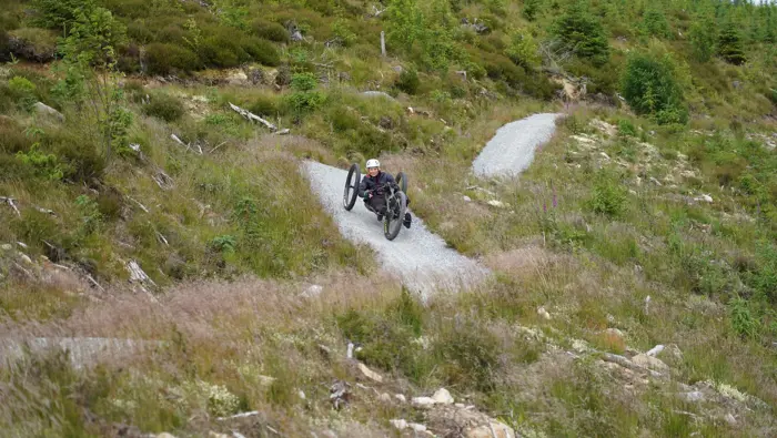 Rider on an adaptive bike going down a steep hill.