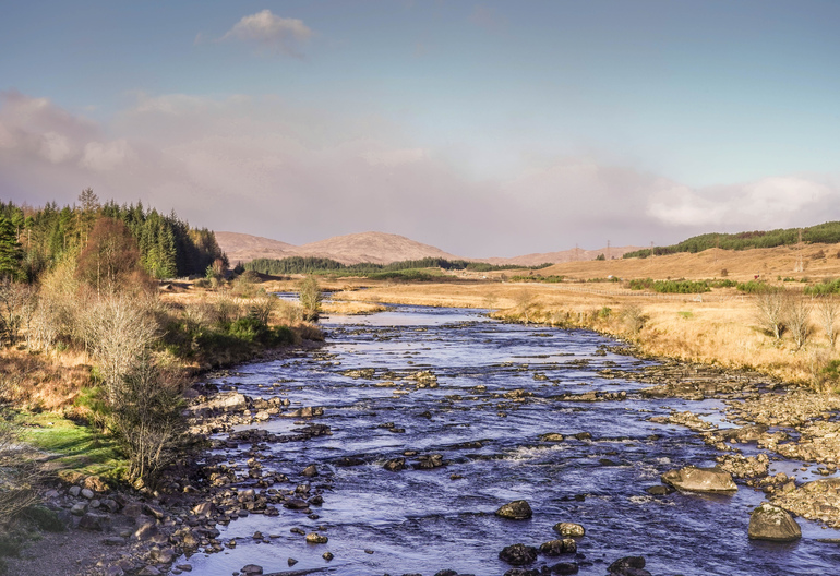 A stream in a field with mountains behind