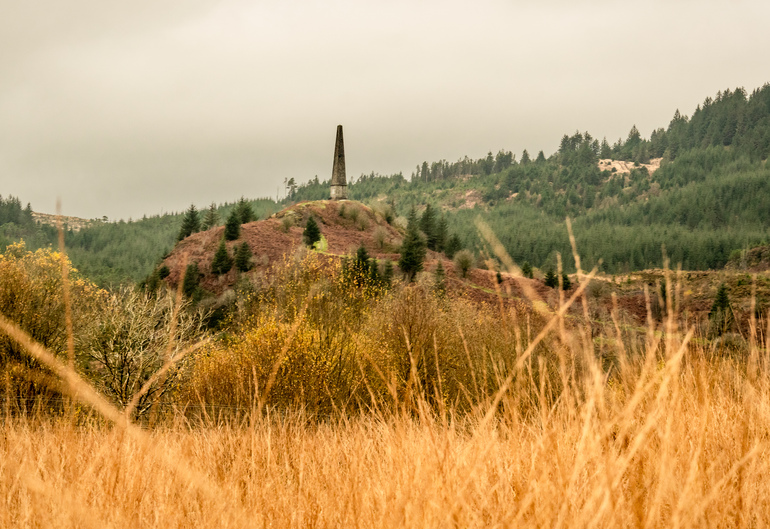 A stone monument through the grass on a hill 