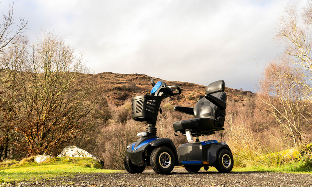A mobility scooter sitting on a wide path with a hill behind