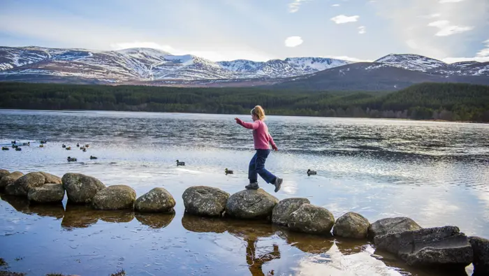 Child balancing on some stones at the edge of the loch.