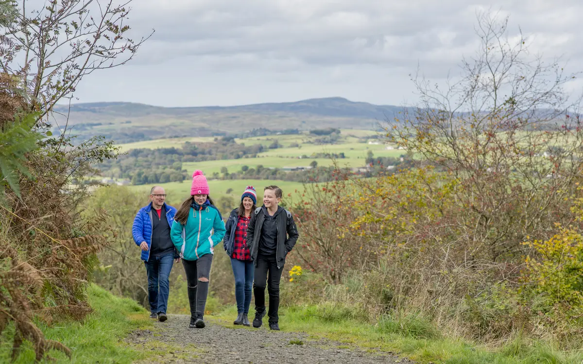 Family walking along a hilltop with views of fields in background