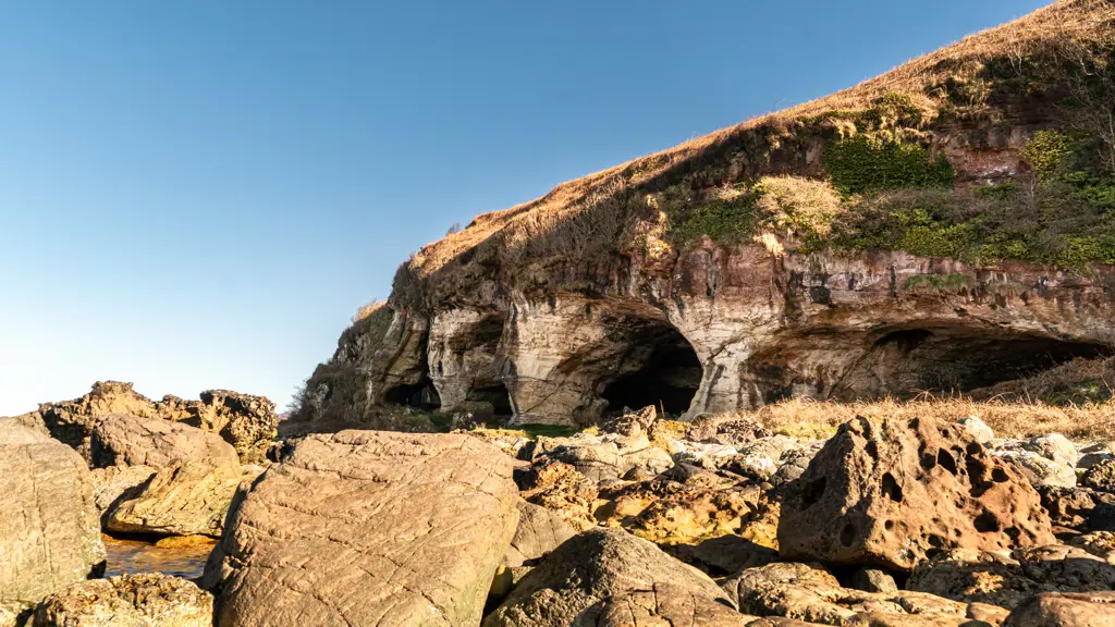 Rocks and cave in the foreground with cliffs in the background.