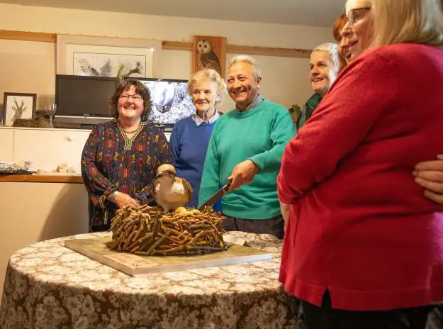 Group of people standing around a cake