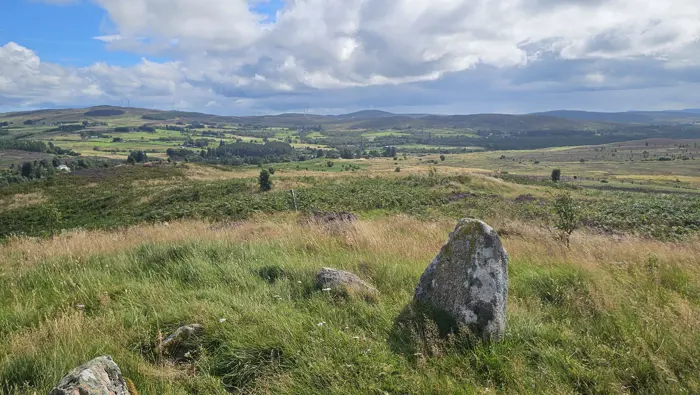 Stone in the foreground with rolling hills and forests in the background.