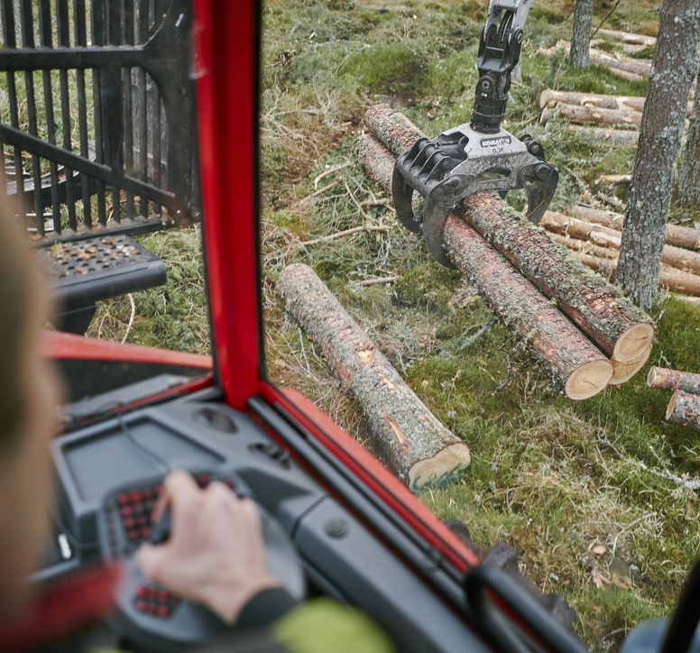 View through the cab of a harvester looking at cut logs