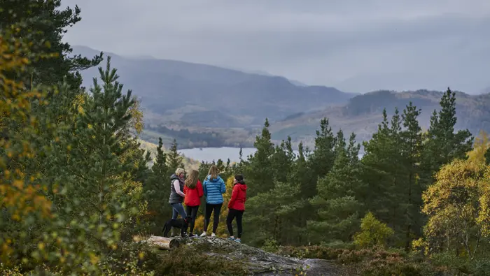 Four people standing on a rock with expansive views to the hills.