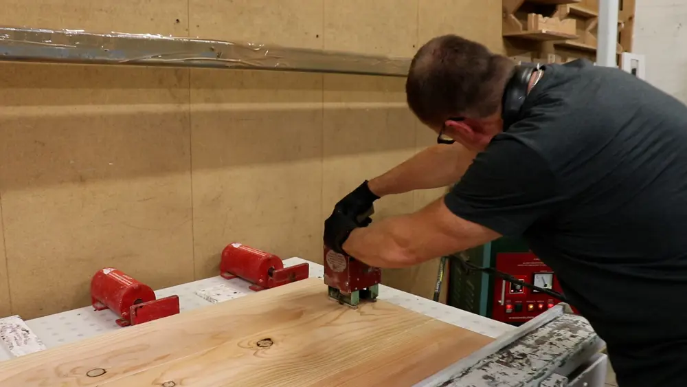 Man pressing a machine into a plank of wood