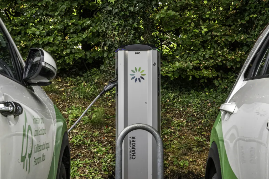 Two cars sitting next to a ev charger