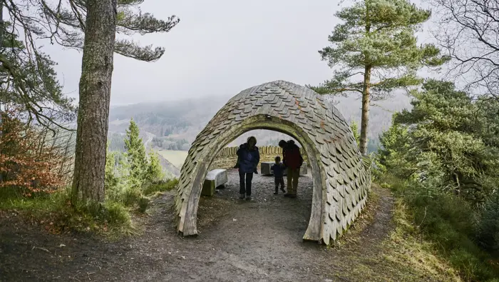 People under a sculpture at a viewpoint.