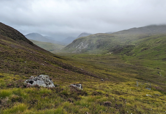 A view down a glen between misty mountains 