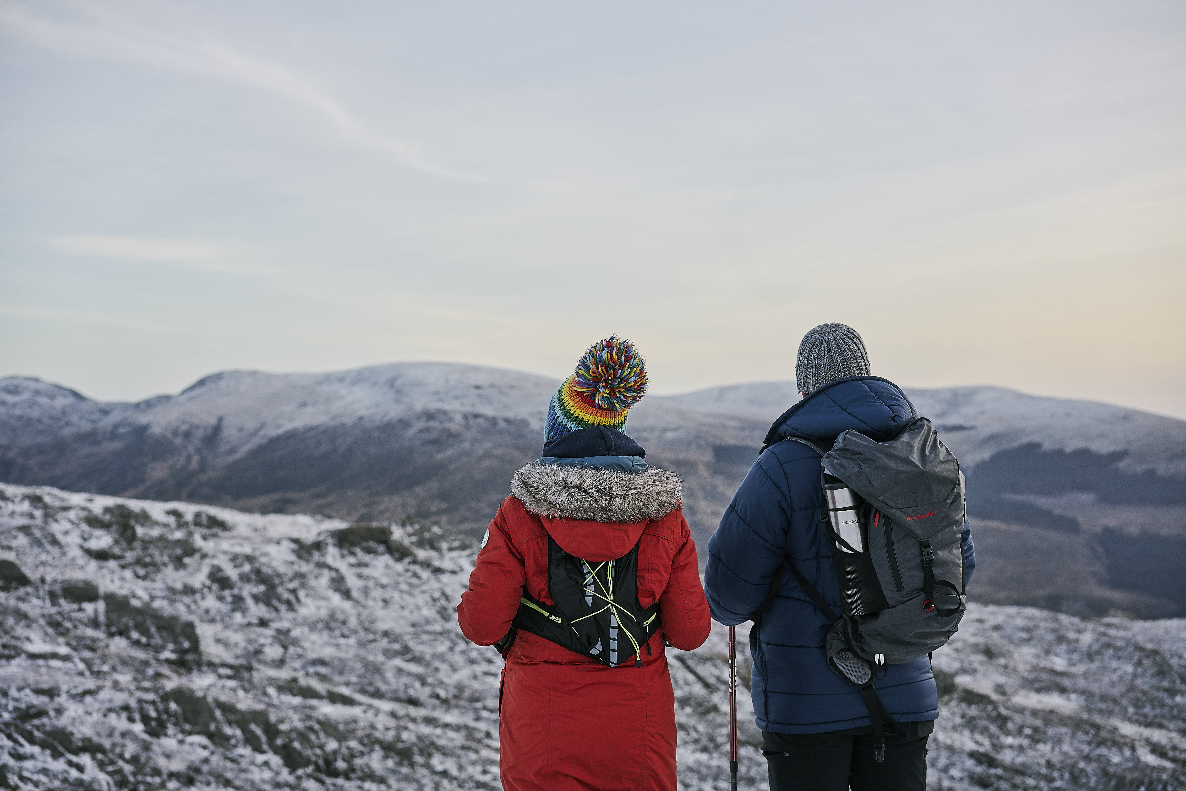 Couple facing a snowy landscape with hills in the distance
