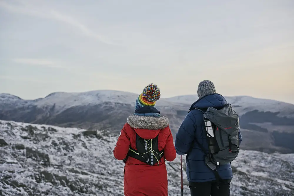 Couple facing a snowy landscape with hills in the distance