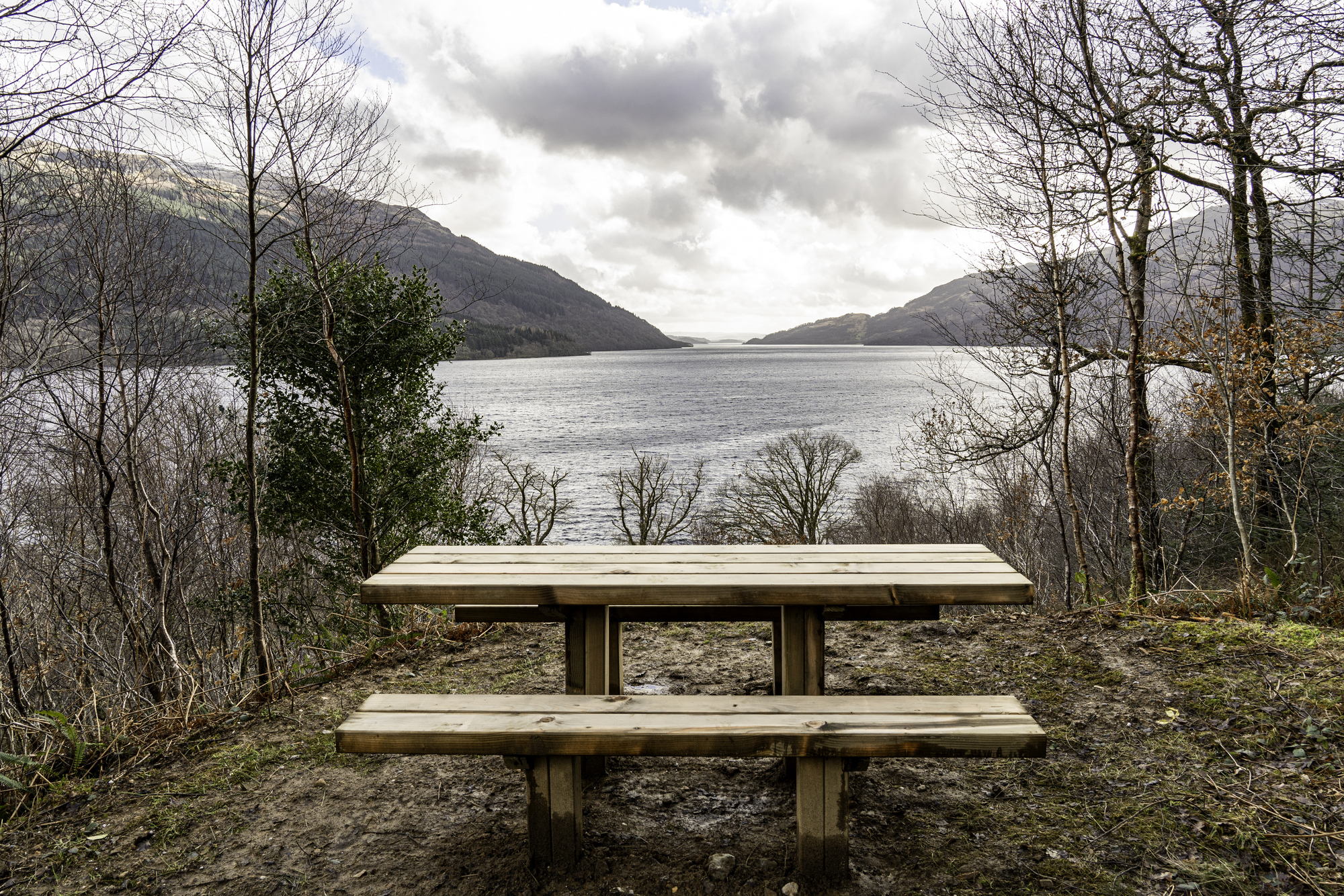 A wooden picnic bench overlooking a loch